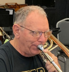 Len smiling holding a trombone